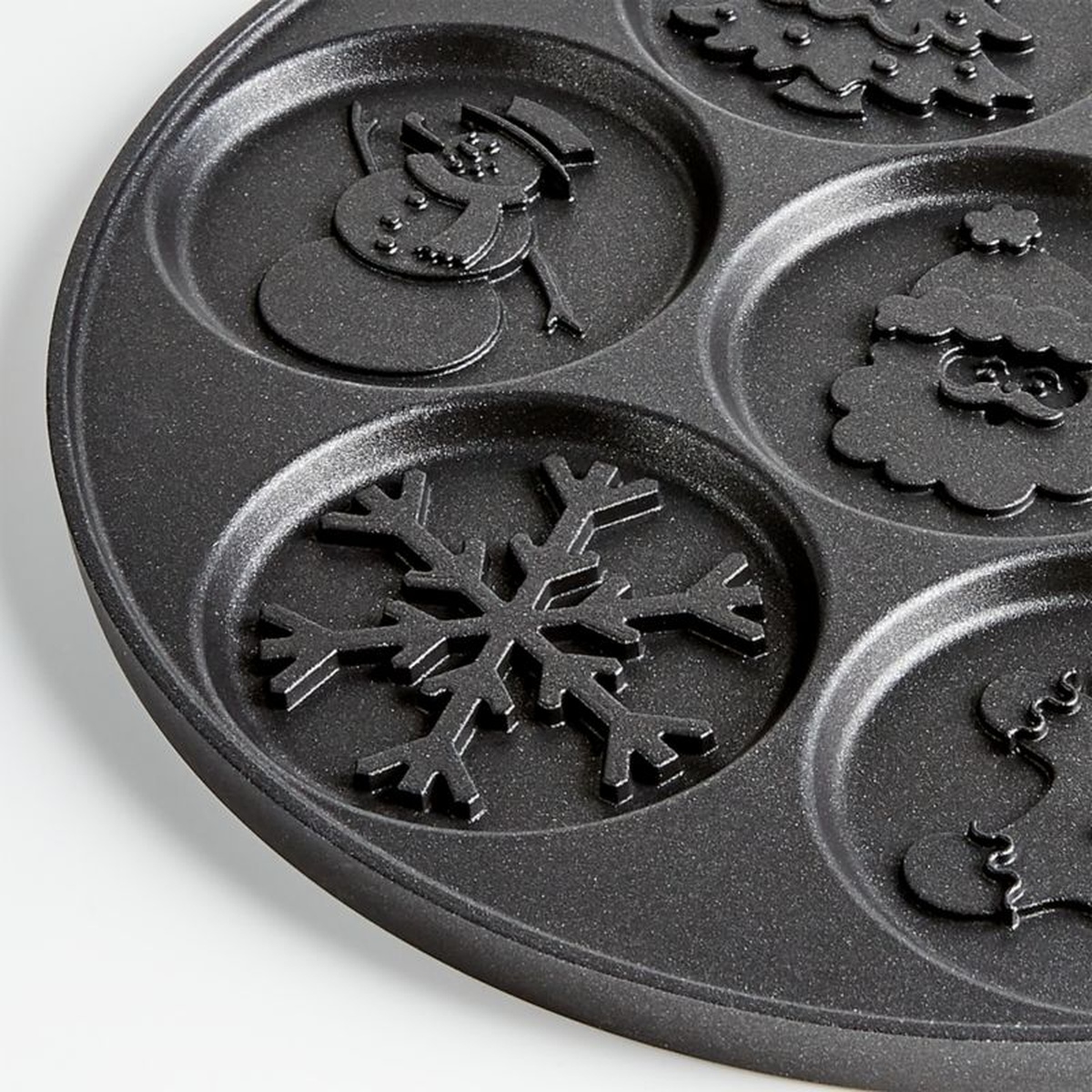 Close-up detail of Nordic Ware Holiday Pancake Pan molds showing snowflake, snowman, and Santa embossed designs