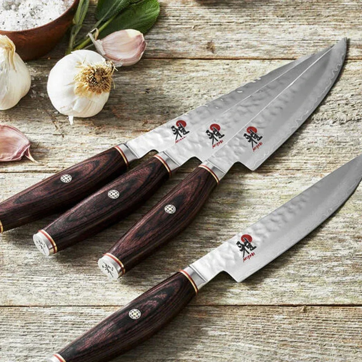 Miyabi Artisan steak knives displayed on a rustic wooden surface with garlic