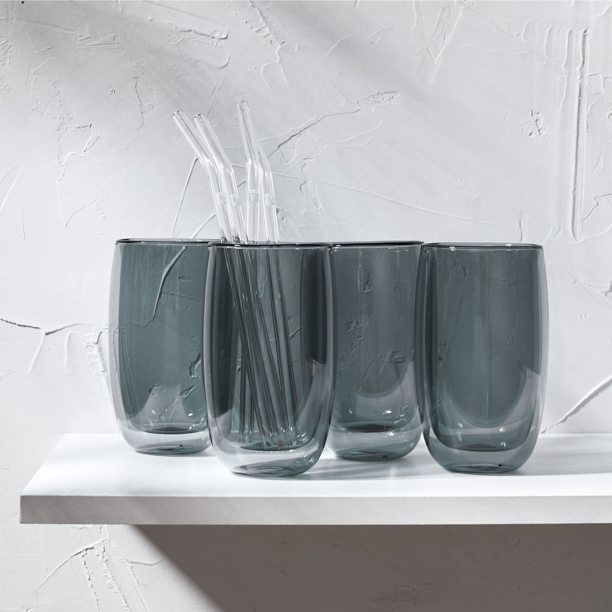 Four ZWILLING Sorrento smoke grey double wall latte glasses with clear bent glass straws displayed on a white shelf
