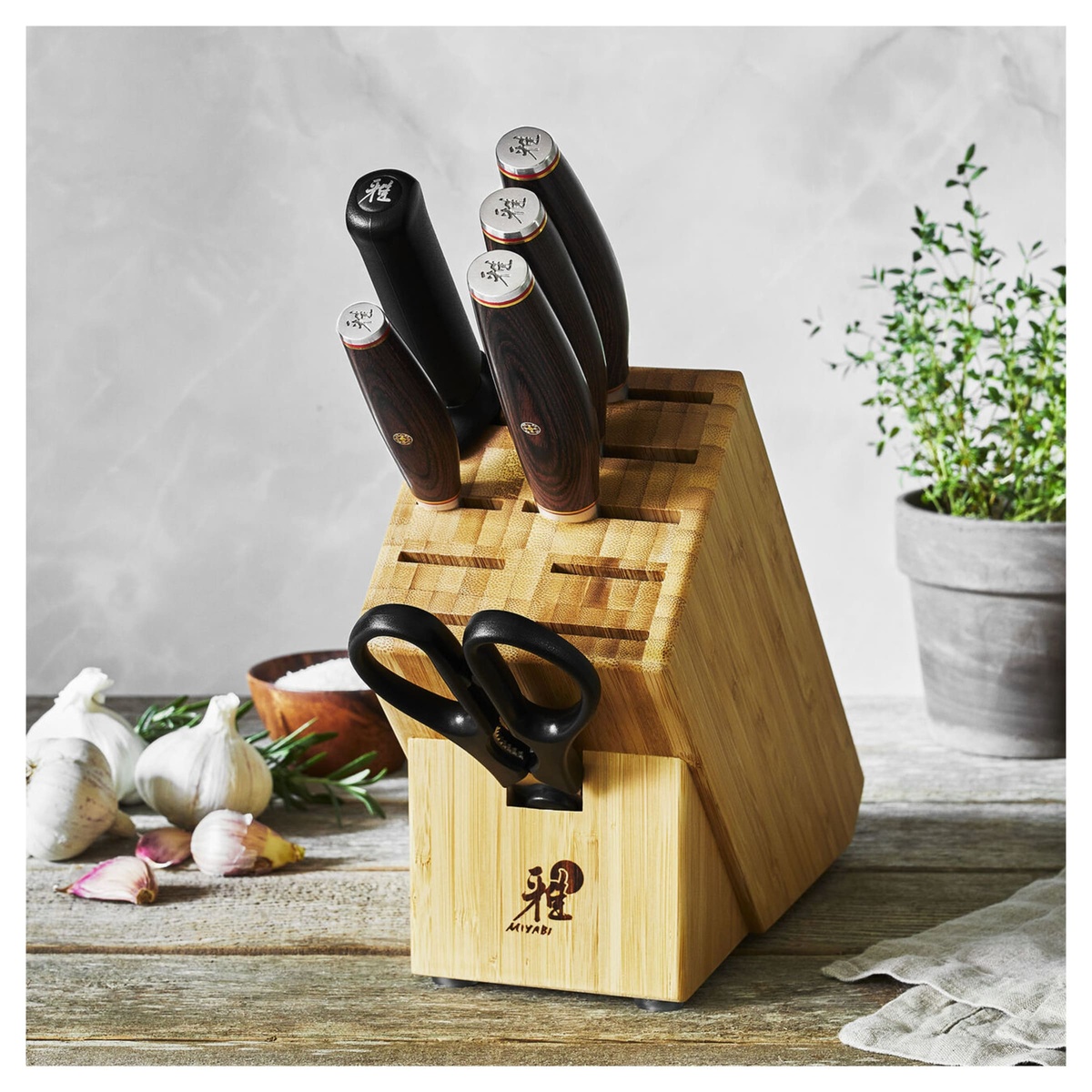 Miyabi Artisan knife set displayed on a wooden table with fresh garlic