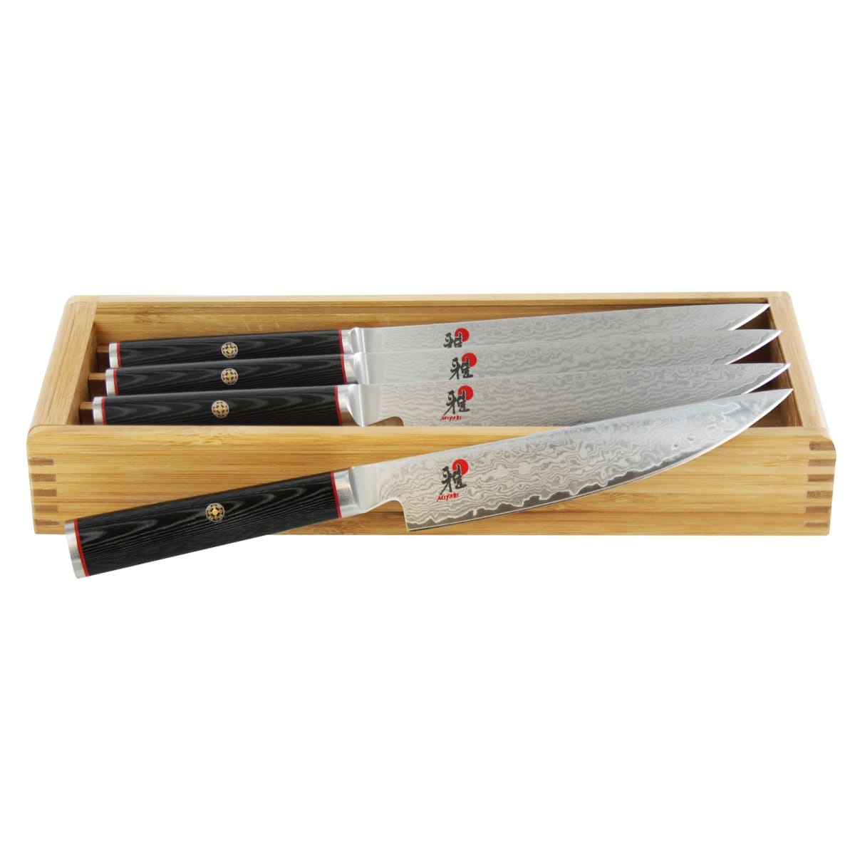 Miyabi Kaizen 4-piece steak knife set with Damascus blades and black Micarta handles displayed in a bamboo storage box
