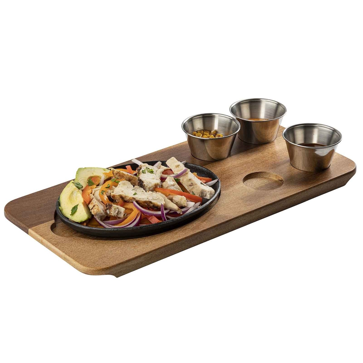 TableCraft 10709 acacia fajita serving board displayed with an oval cast iron skillet of chicken fajitas and three stainless steel ramekins