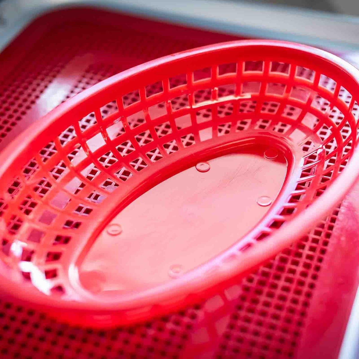 Close-up interior view of a red oval plastic serving basket showing open lattice weave pattern