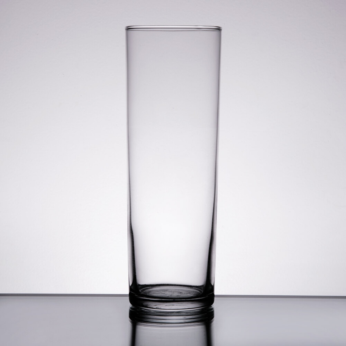 Libbey 115 straight-sided 13.5 oz. zombie glass, tall cylindrical clear glass on a reflective surface