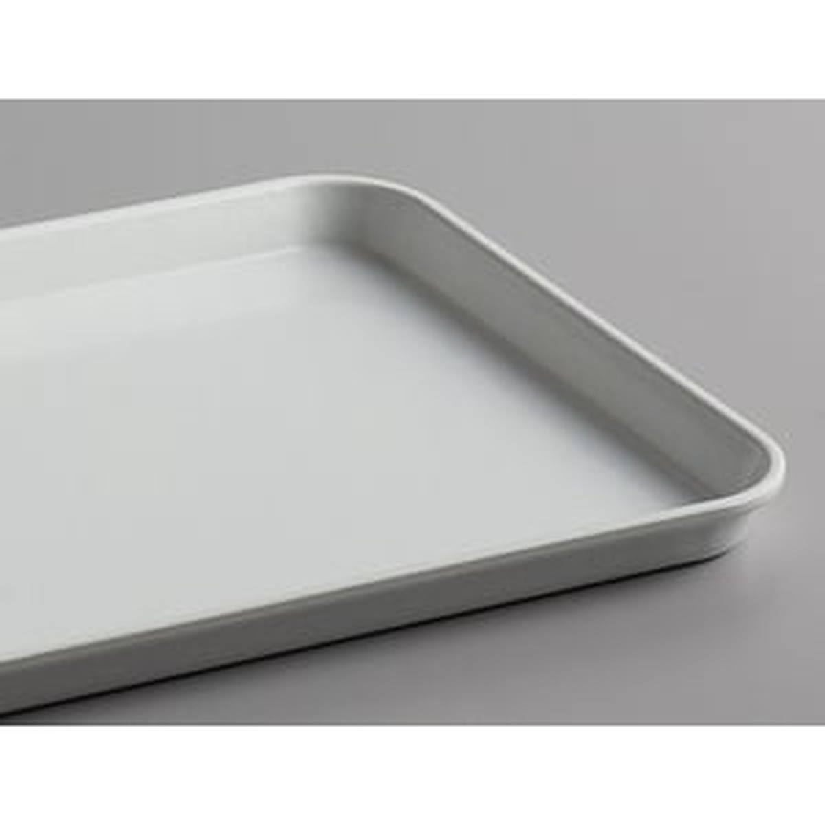 Close-up detail of the rounded corner and shallow rim of the Cambro 1218MT148 white fiberglass market tray