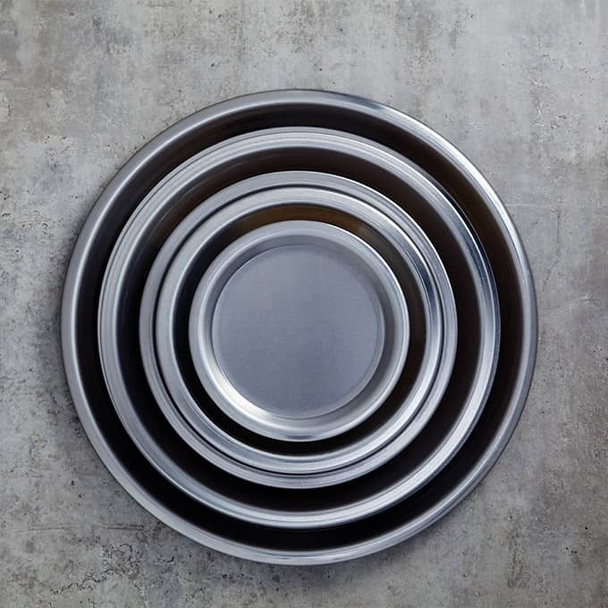 Multiple American Metalcraft stainless steel round pans nested together showing size range