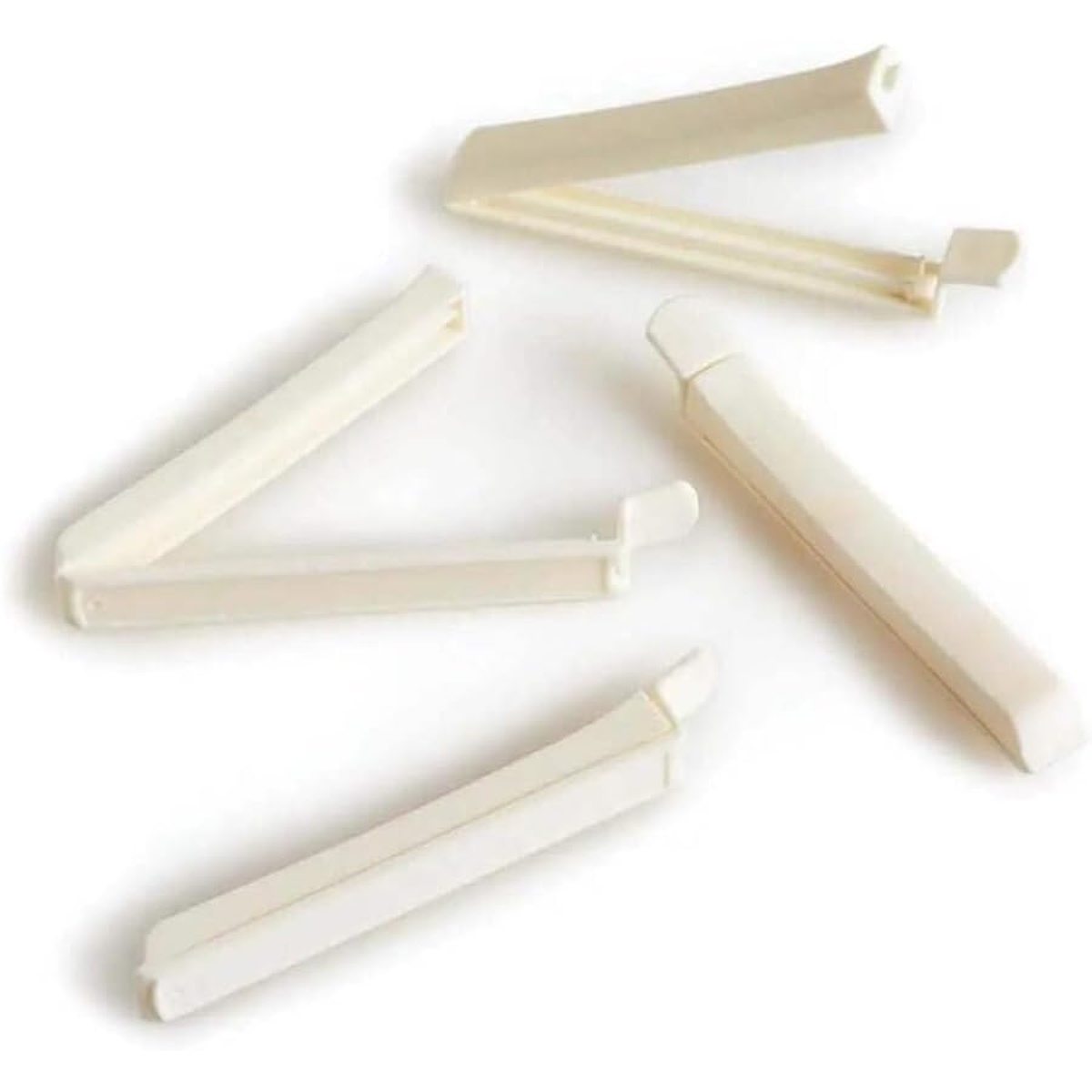 Four white Ateco decorating bag clips scattered on a white background