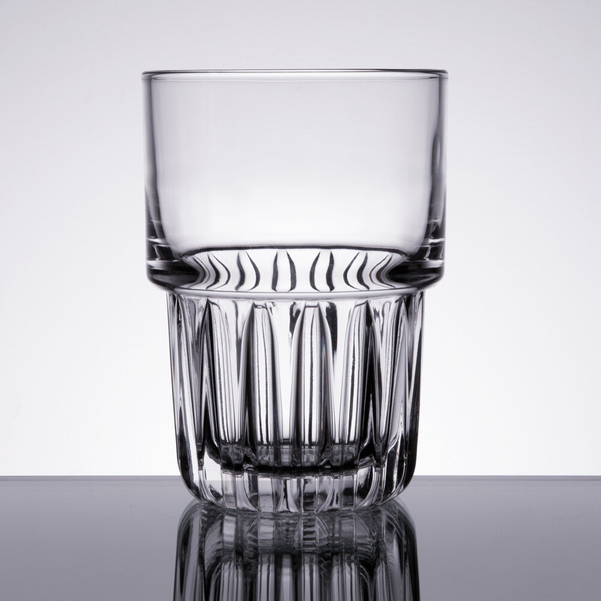 Libbey 15437 Everest 14 oz clear cooler glass with faceted cut base on reflective surface