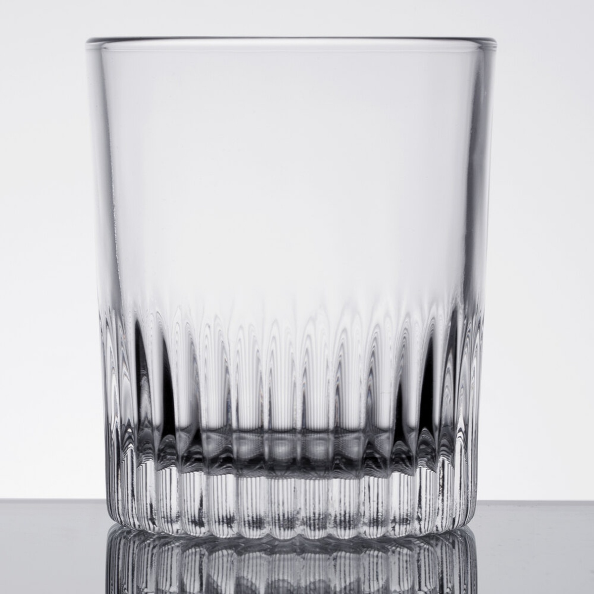 Libbey 15626 8.5 oz rocks glass with decorative ridged base on reflective surface