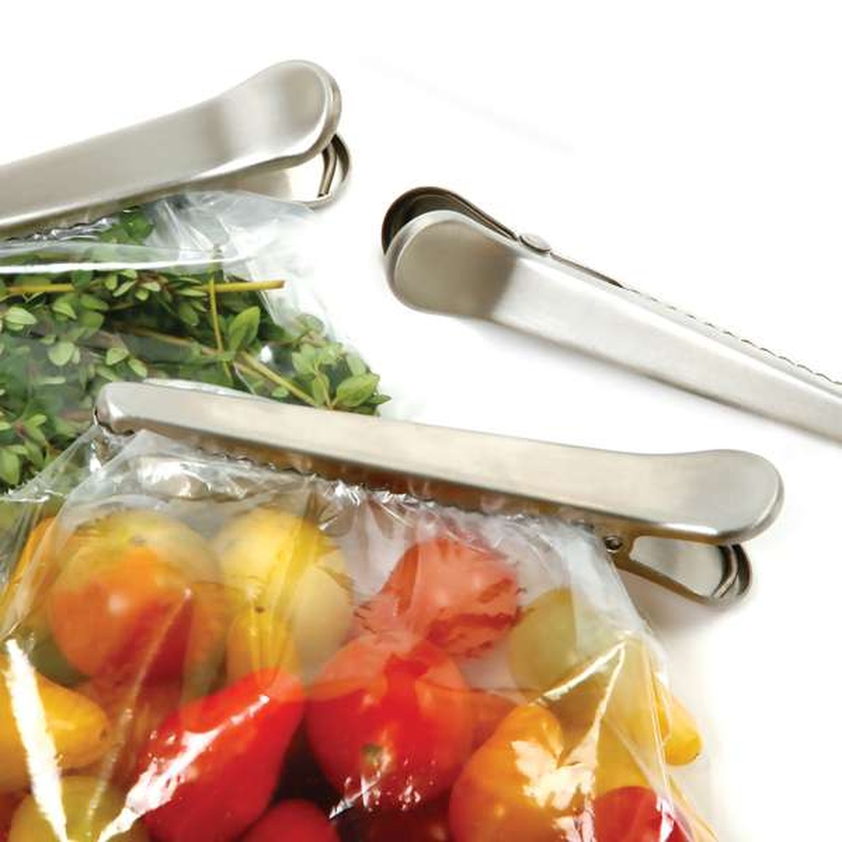 Norpro stainless steel jaw clips sealing plastic bags containing fresh tomatoes and herbs