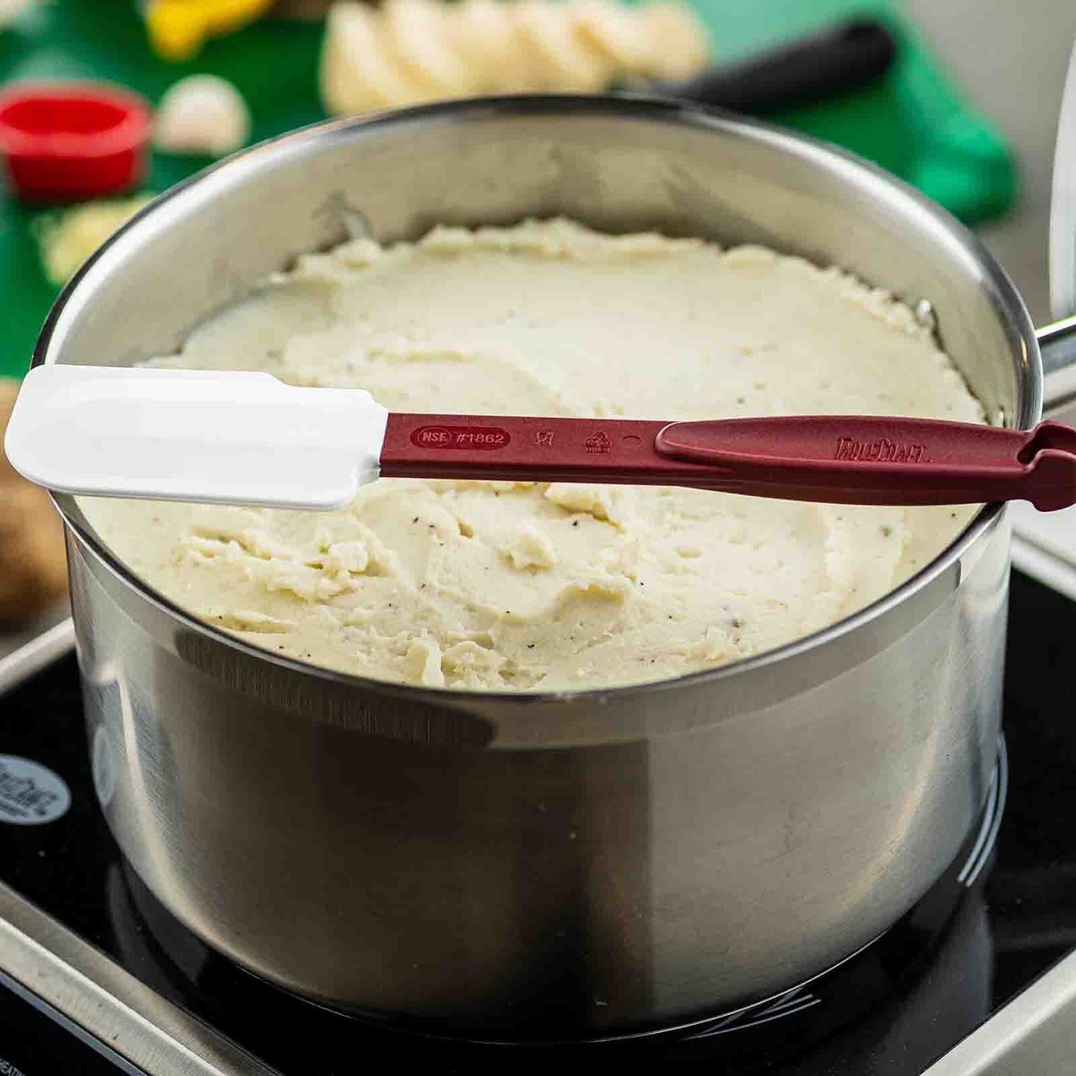 TableCraft 1862 spatula resting across a stainless steel pot of mashed potatoes on an induction burner