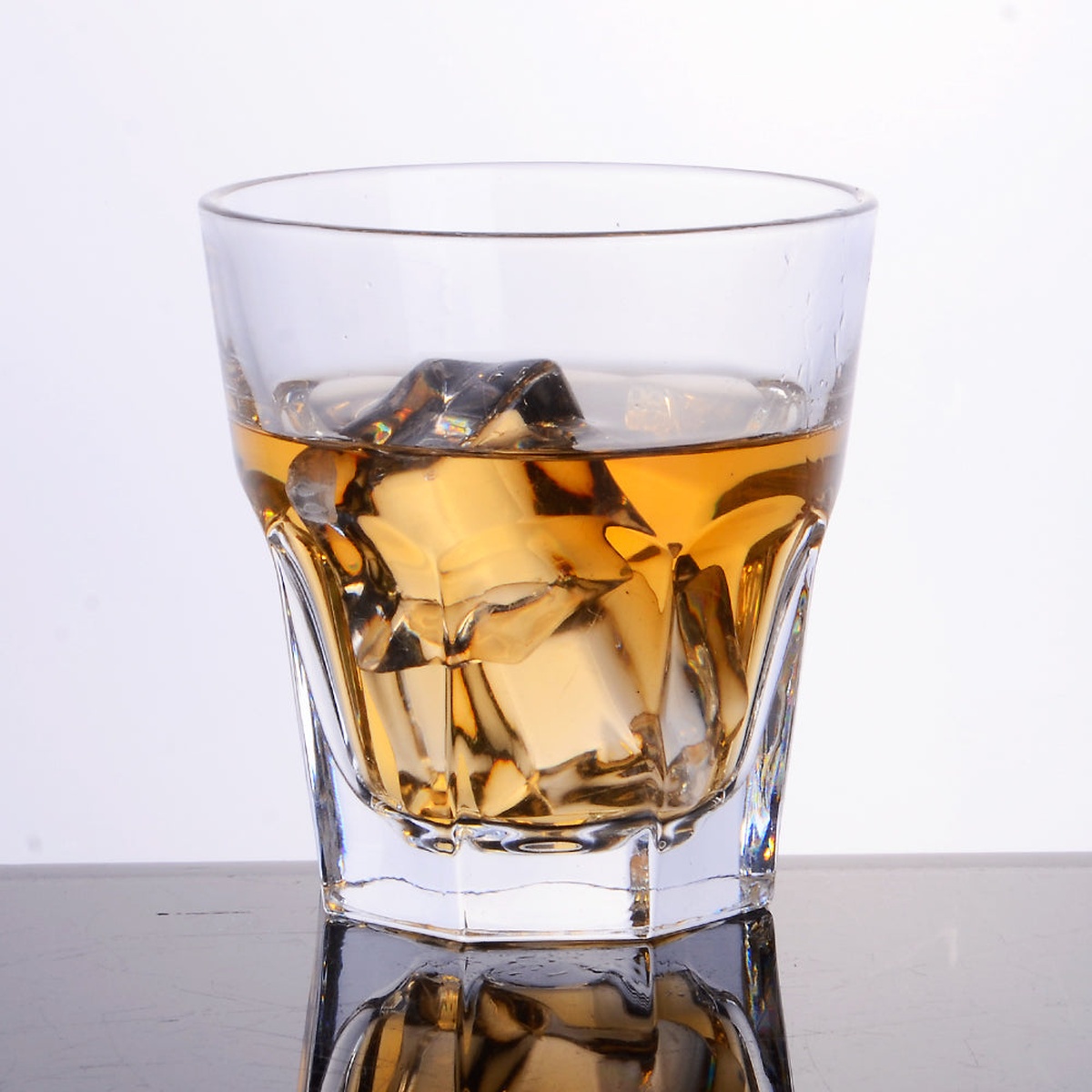 Enhanced 9 oz glass tumbler filled with amber spirit and ice cubes, reflecting on a dark surface