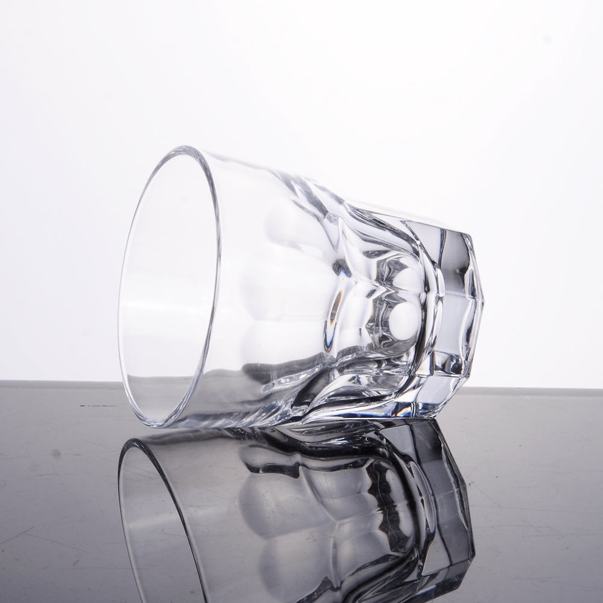 Enhanced 9 oz glass tumbler tipped on its side showing the thick faceted base and molded bottom detail