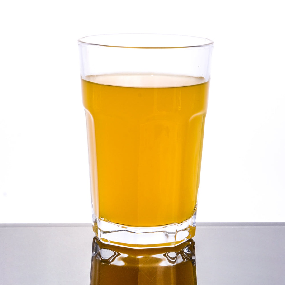 Enhanced Glassware 2015 14 oz. clear glass tumbler filled with amber beverage on reflective surface
