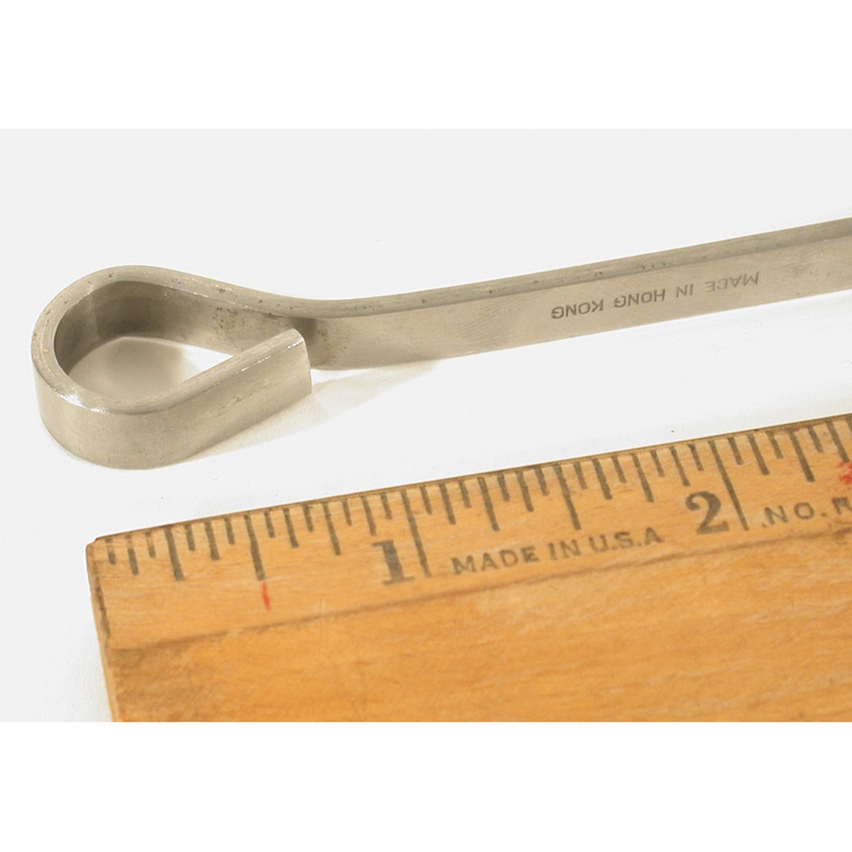 Close-up of the ring end of a flat stainless steel skewer shown next to a ruler for scale