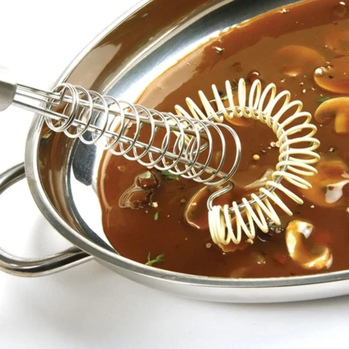 Norpro Saucinator Whisk silicone coil end submerged in a rich brown gravy inside a stainless steel pan