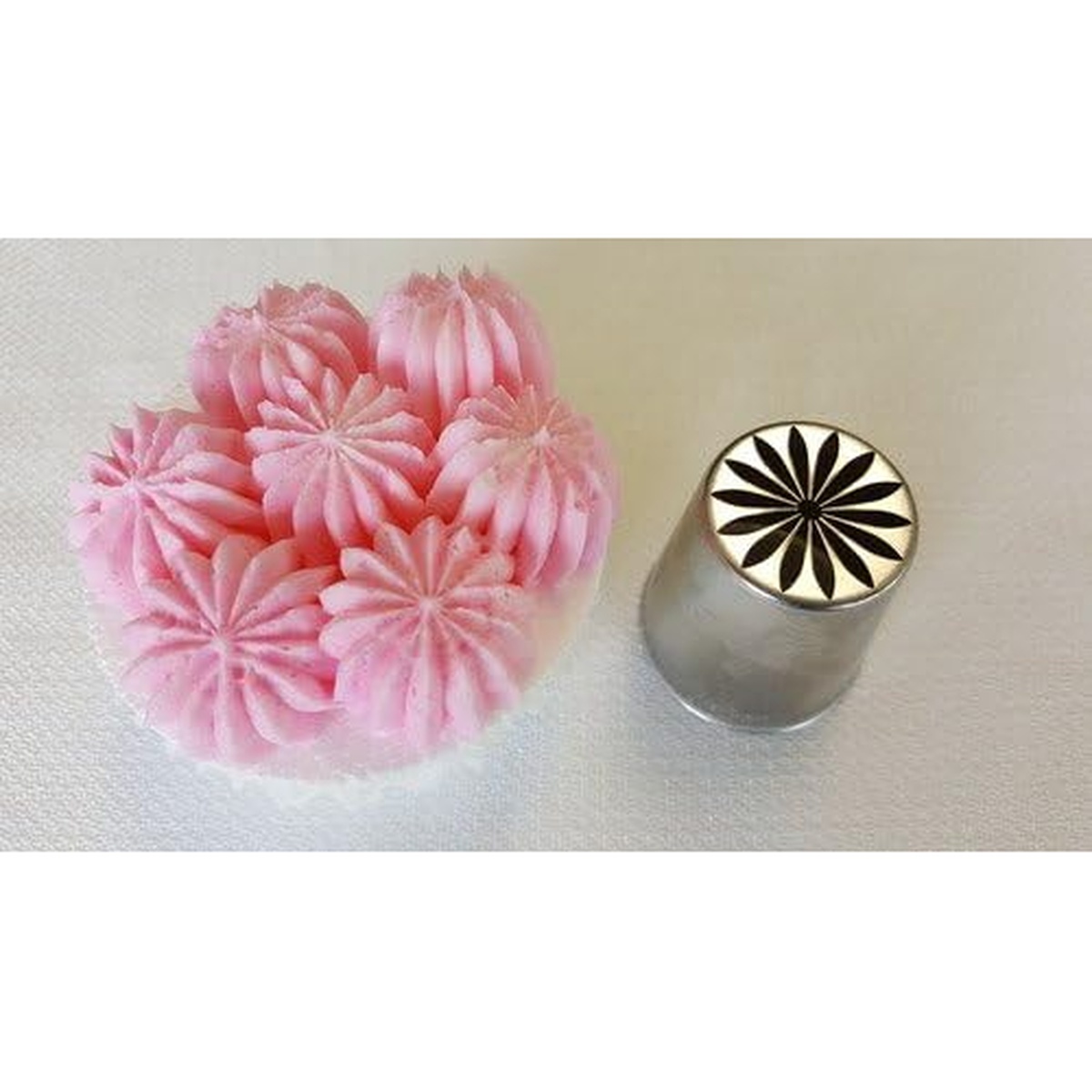 Ateco 249 Russian piping tip shown beside pink tulip rose floral piping designs on a white surface
