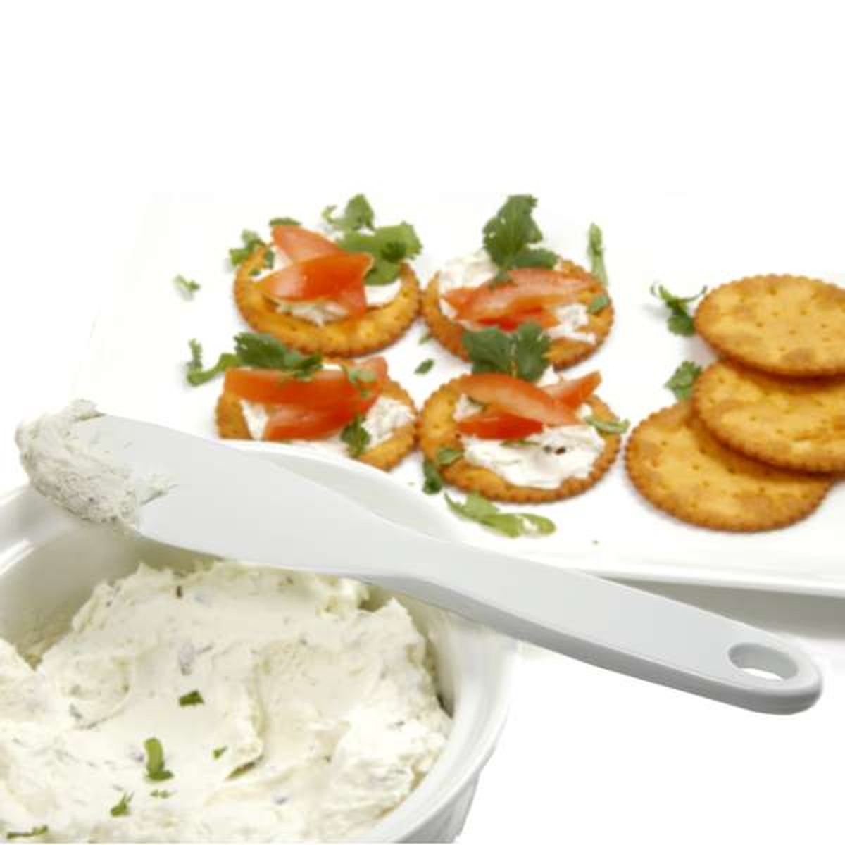 Norpro spatula scraper spreading cream cheese, with crackers topped with cream cheese and tomato in background
