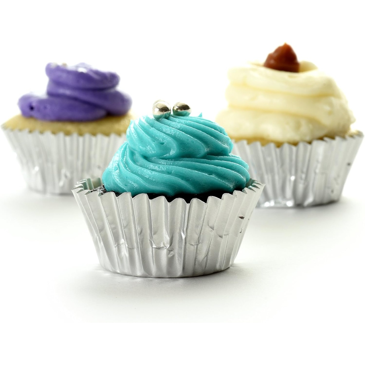 Three mini cupcakes with teal, purple, and vanilla frosting displayed in Norpro silver foil baking cups