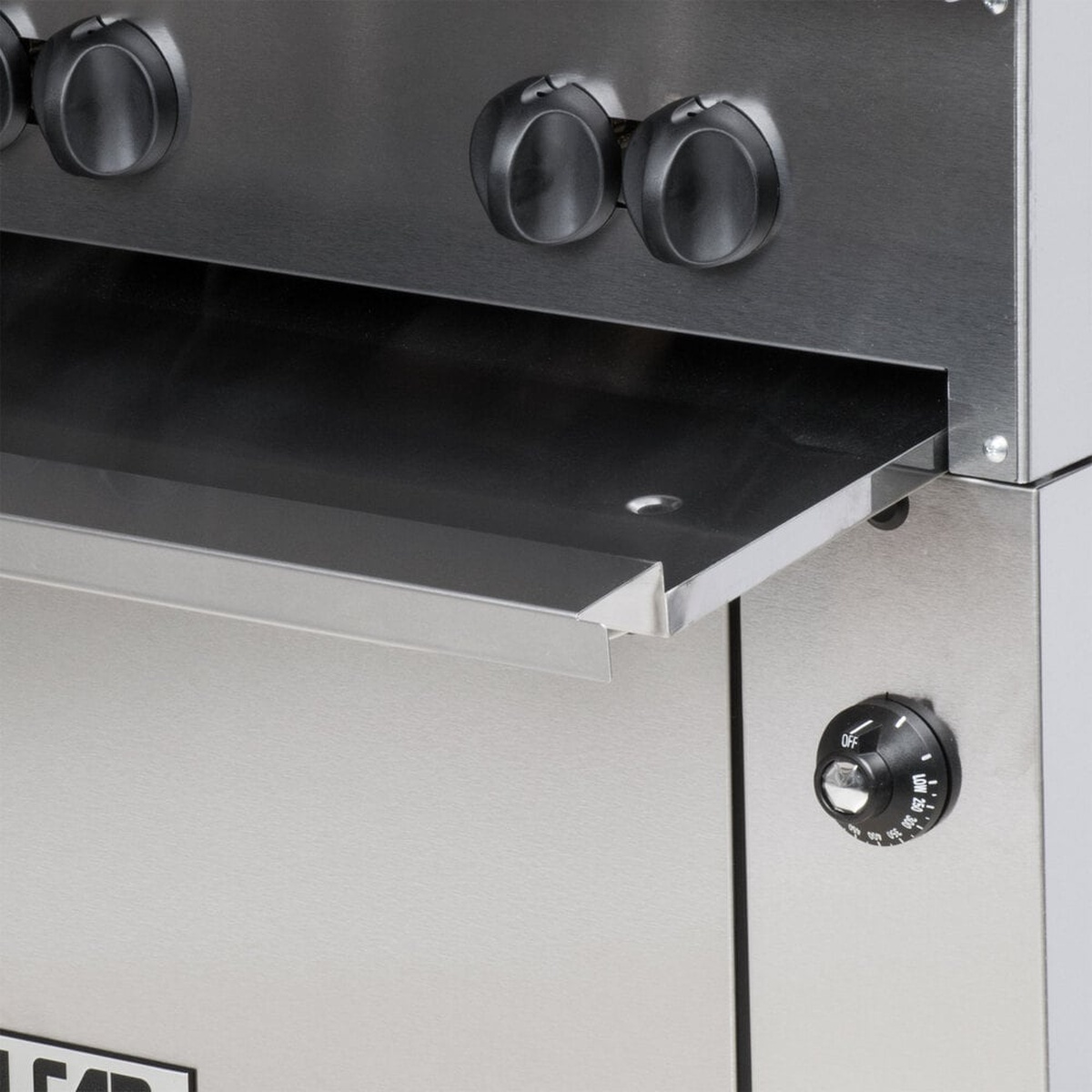 Close-up of pull-out stainless steel crumb tray and oven temperature control knob
