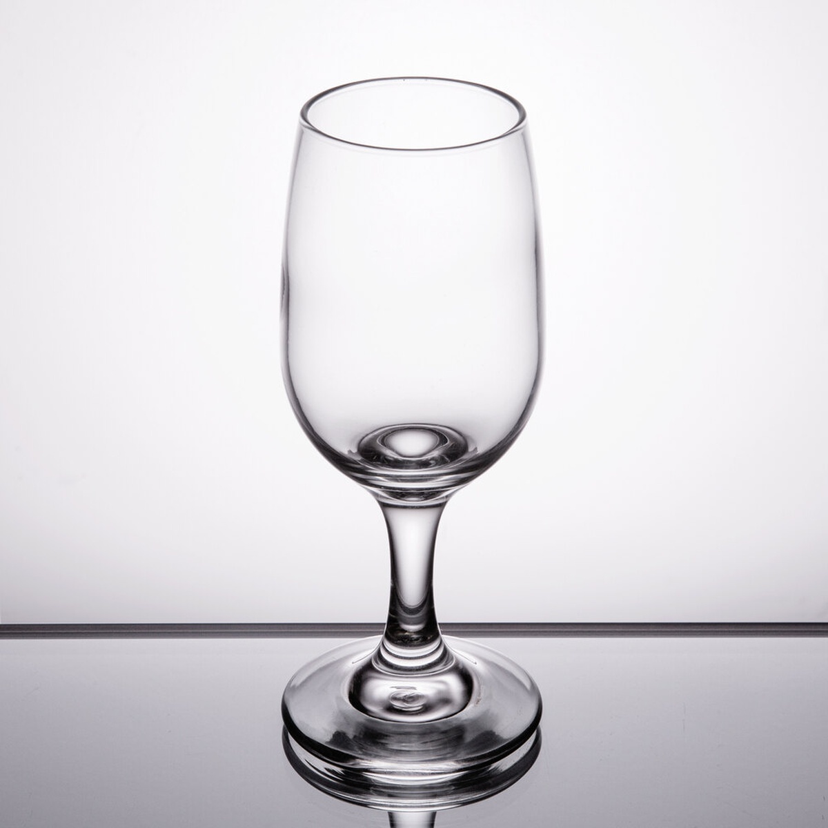 Libbey Embassy 3766 6.5 oz clear stemmed white wine glass on a reflective surface