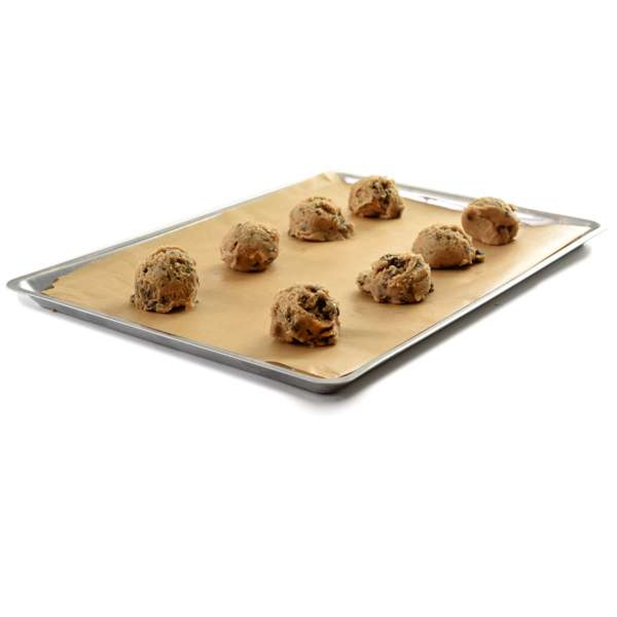 Stainless steel baking pan lined with parchment paper and topped with raw cookie dough balls ready to bake