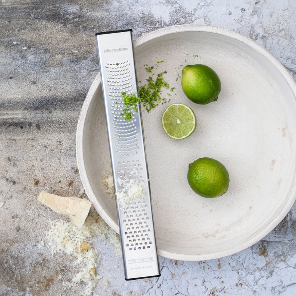 Microplane dual zester being used with fresh limes and hard cheese