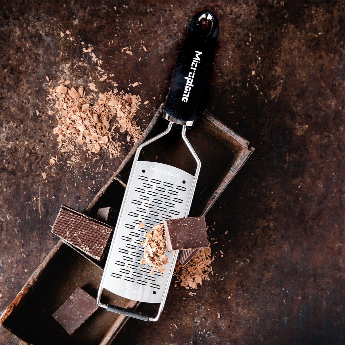 Microplane ribbon grater being used to grate chocolate into fine curls