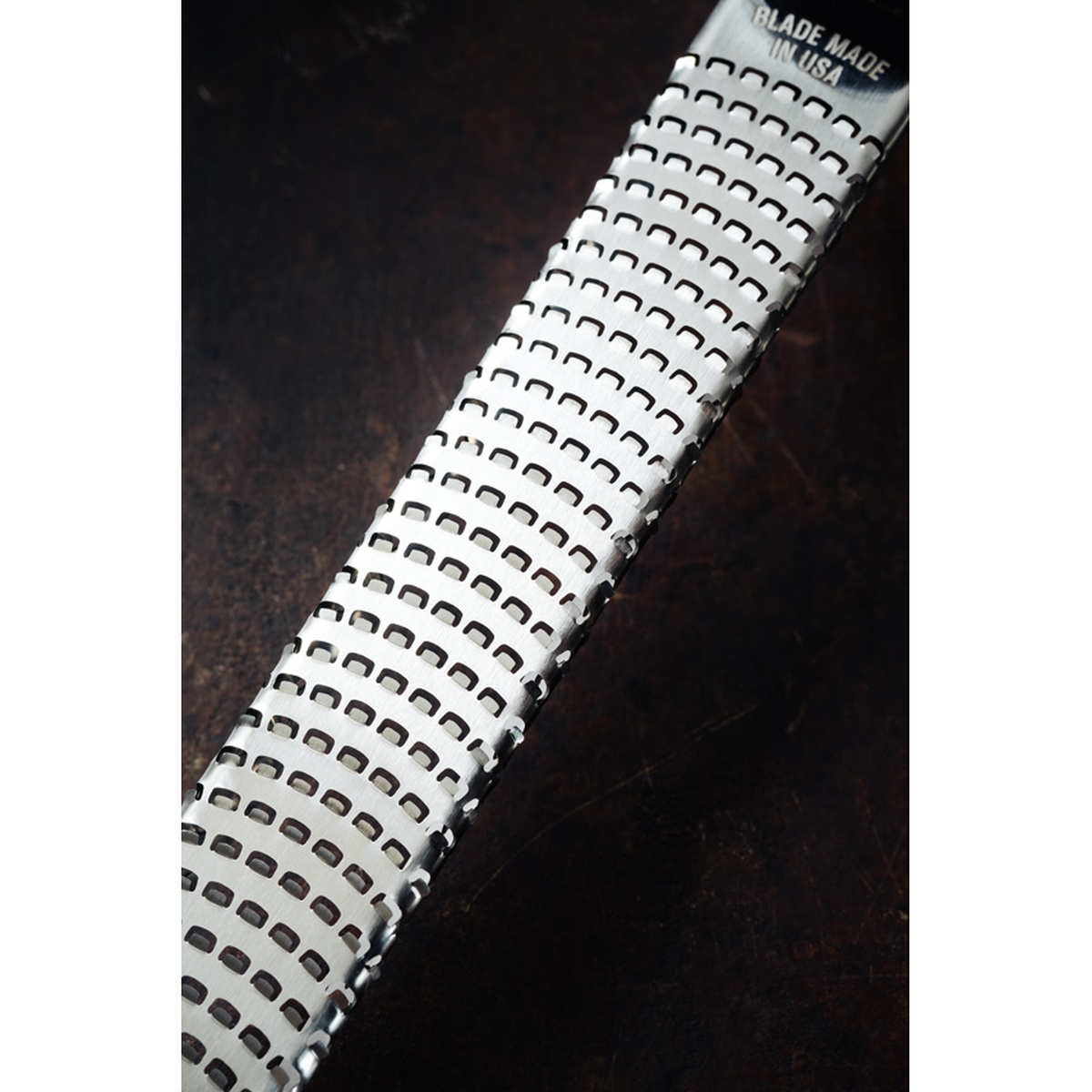 Close-up detail of the Microplane zester grater stainless steel blade surface showing photo-etched teeth with 'Blade Made in USA' marking