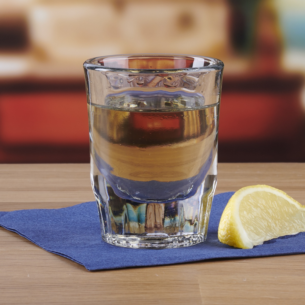 Anchor Hocking 5282U 2 oz. fluted whiskey shot glass filled with amber spirit on a blue napkin