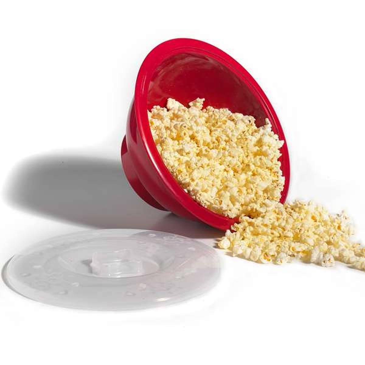 Norpro Microwave Popcorn Popper red bowl tilted with freshly popped popcorn spilling out, clear lid in foreground