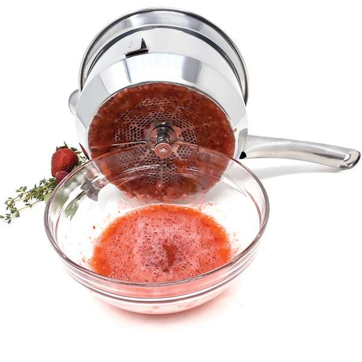 Food mill straining strawberry puree into a glass bowl
