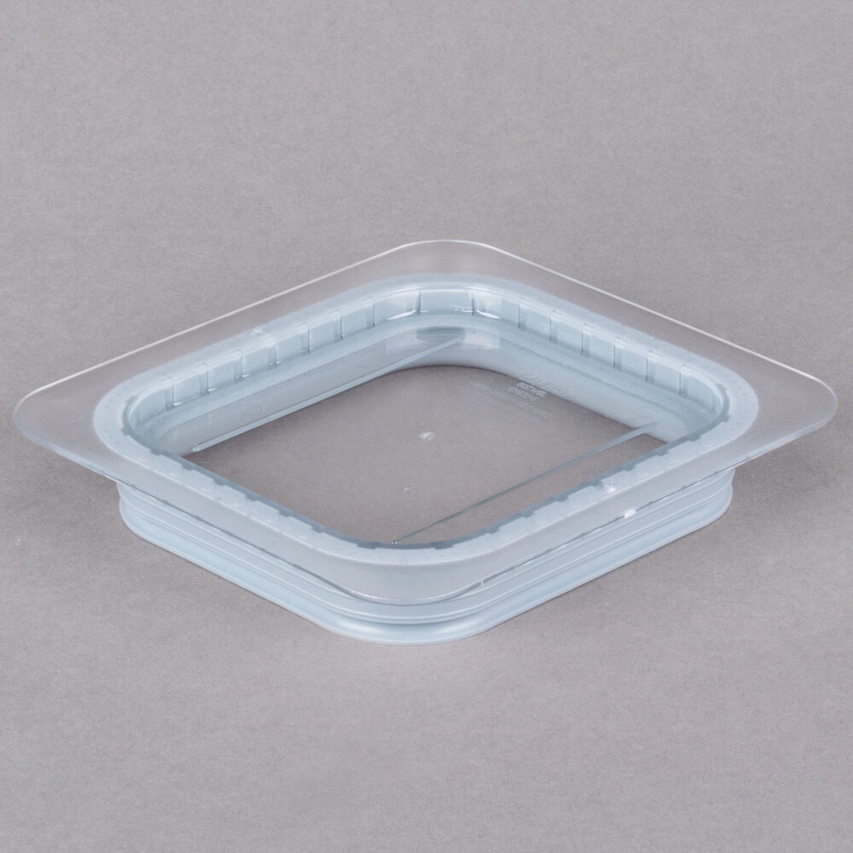 Cambro 60CWGL135 1/6 size clear polycarbonate GripLid cover, angled view showing molded gasket and thumb tabs on neutral background