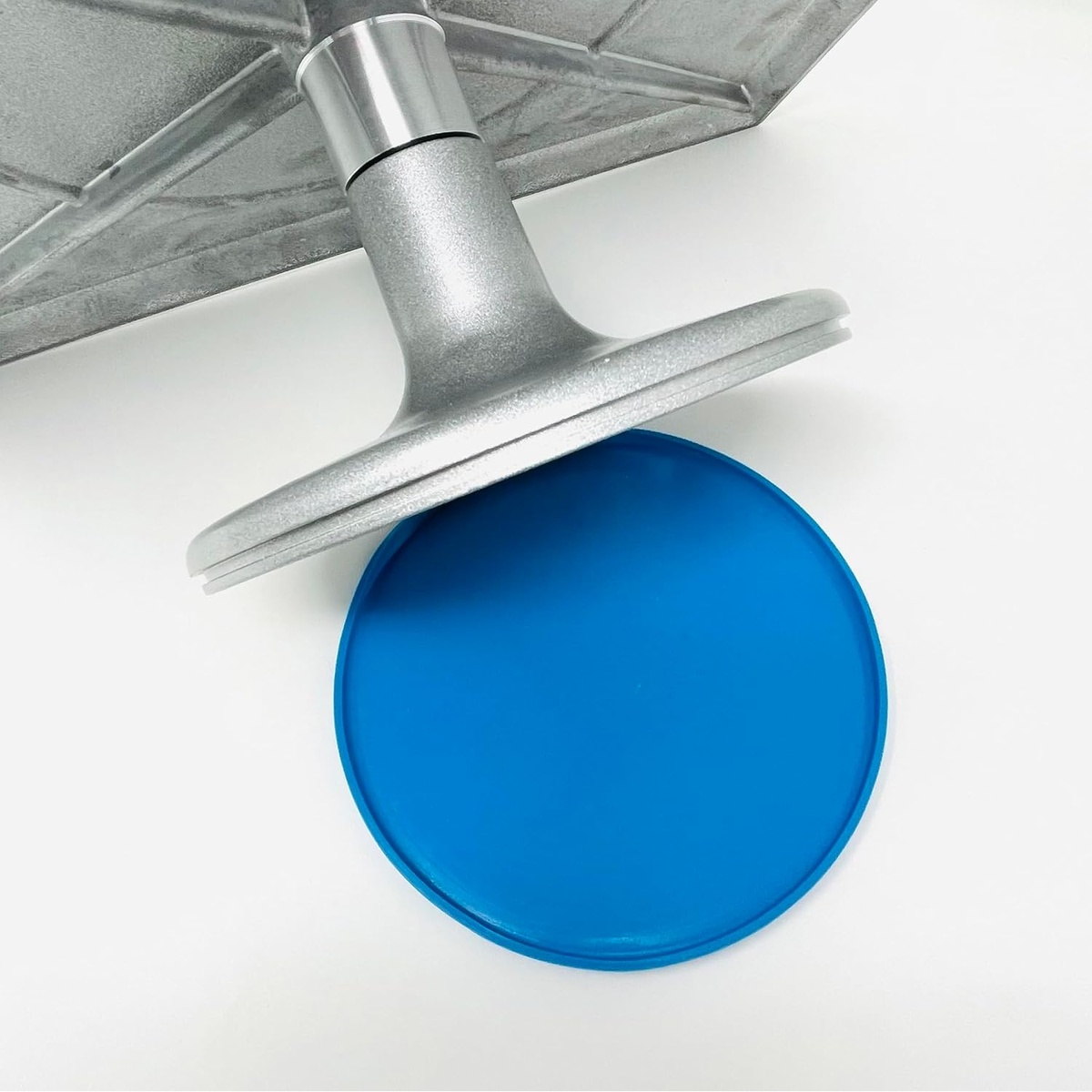 Underside of Ateco 614 turntable showing the round blue silicone non-slip base cap and aluminum pedestal stem