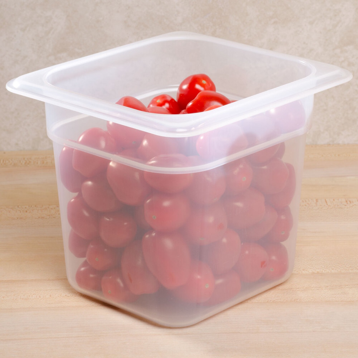 Cambro 66PP190 translucent food pan filled with cherry tomatoes on a wooden prep surface