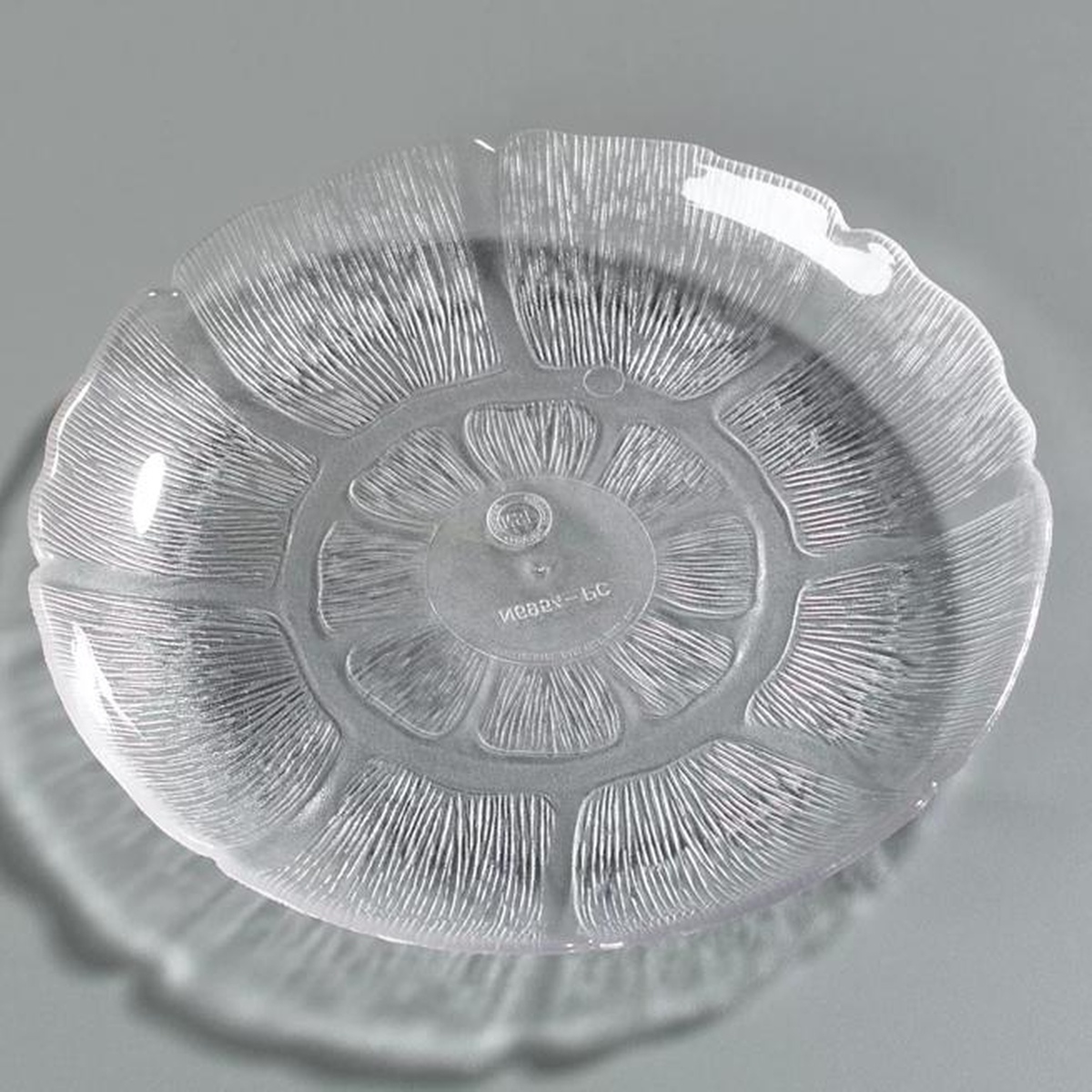 Carlisle Petal Mist clear plate slightly angled view on gray background showing floral relief pattern