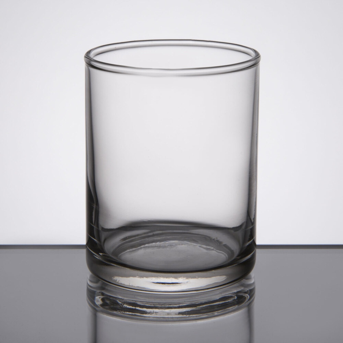 Libbey 763 clear glass votive shot glass with thick base on a reflective surface