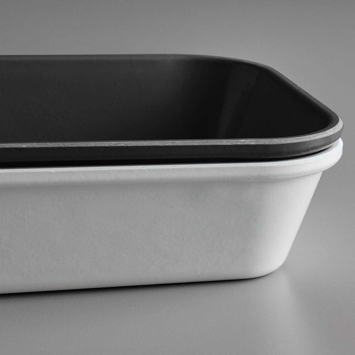 Close-up corner detail of black fiberglass market tray stacked on a white tray, showing Dri-Stak stacking lug separators