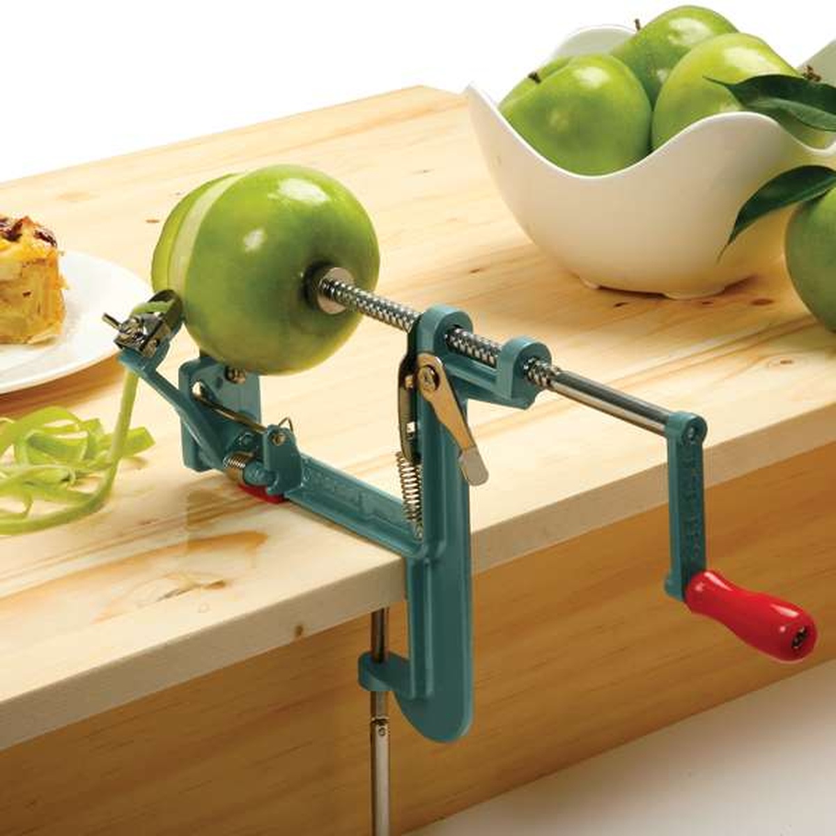 Norpro Apple Mate 3 peeling a green apple on a wooden countertop