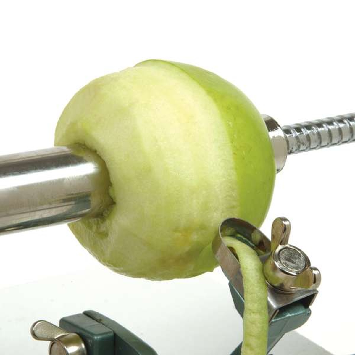 Close up of the stainless steel blade peeling a green apple