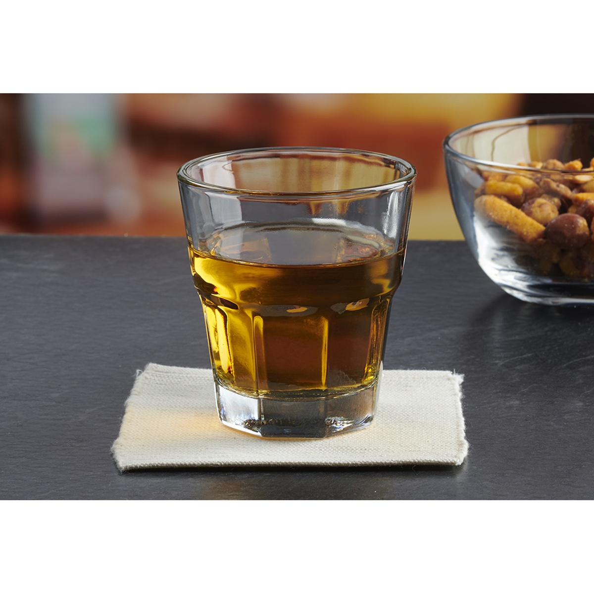 Anchor Hocking New Orleans 5 oz rocks glass filled with whiskey, resting on a linen napkin on a dark slate surface