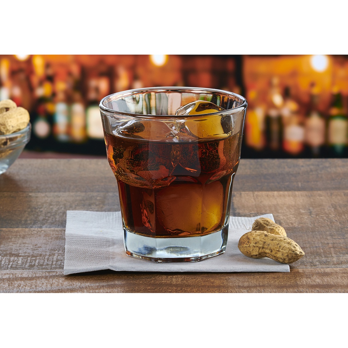 Anchor Hocking 90007 New Orleans 8 oz. rocks glass filled with an amber whiskey drink and ice cubes, resting on a napkin