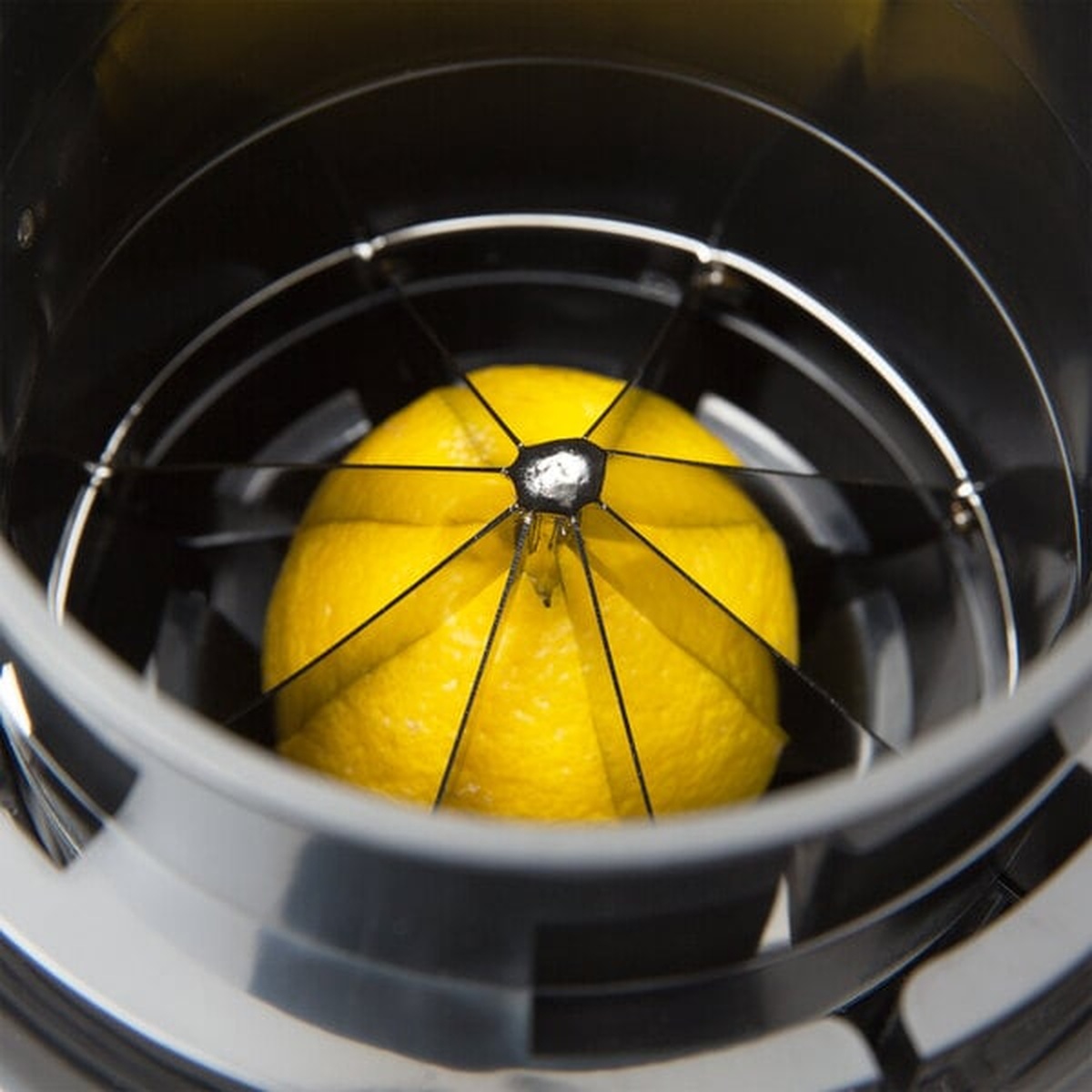 Top-down view of citrus wedger showing lemon positioned under 8-section stainless steel blades