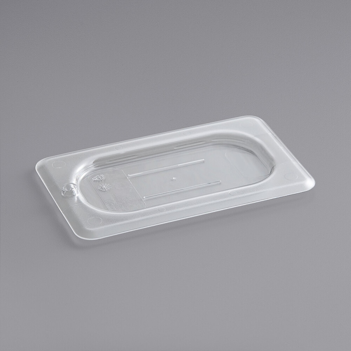 Cambro 90CWC135 1/9 size clear polycarbonate flat lid viewed at an angle on a gray background