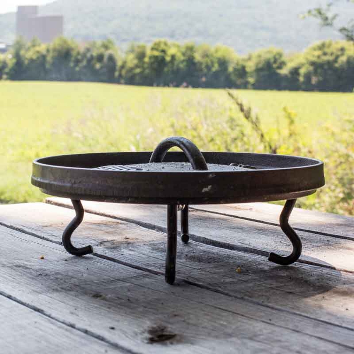 Dutch oven lid resting on the Lodge tool used as a trivet on a wooden table