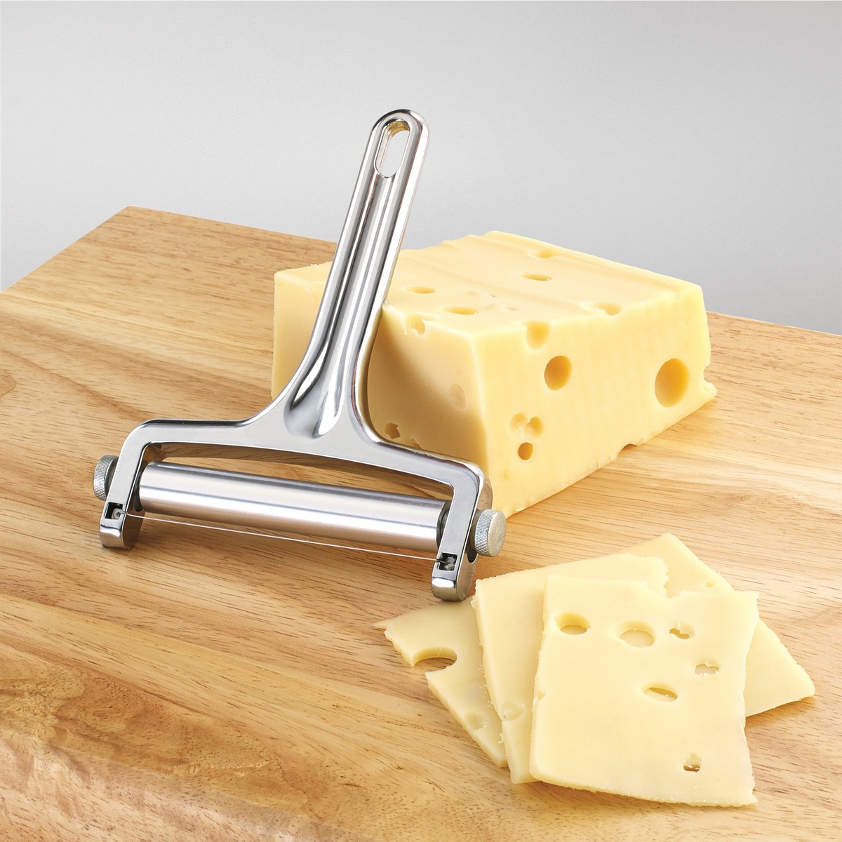 Winco ACS-4 cheese slicer being used to cut slices of Swiss cheese on a wooden cutting board