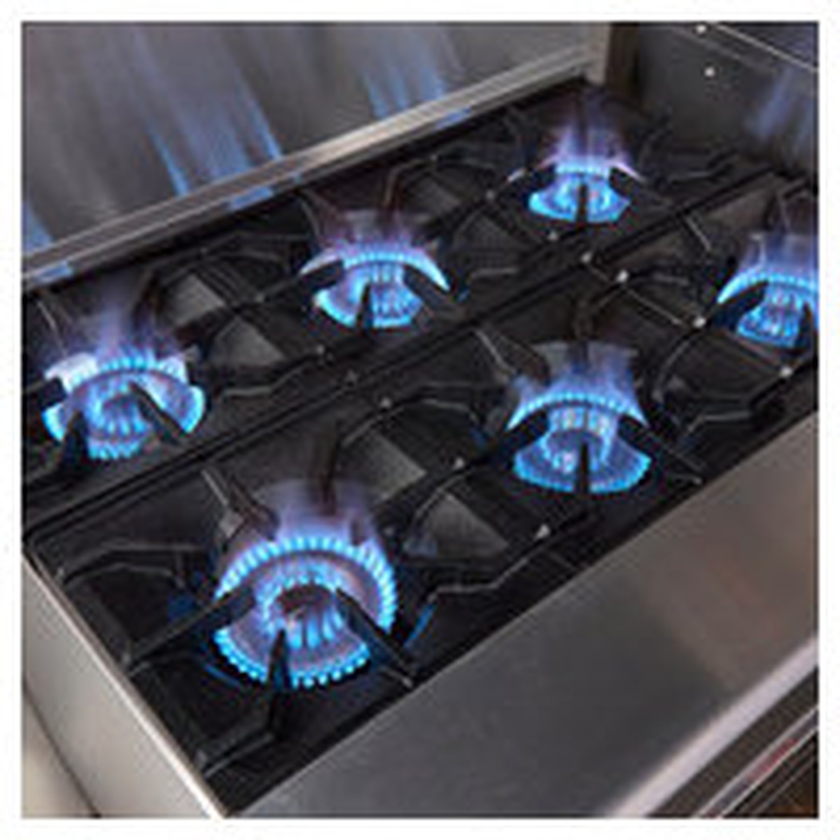 Close-up of gas burners with blue flames under cast iron grates