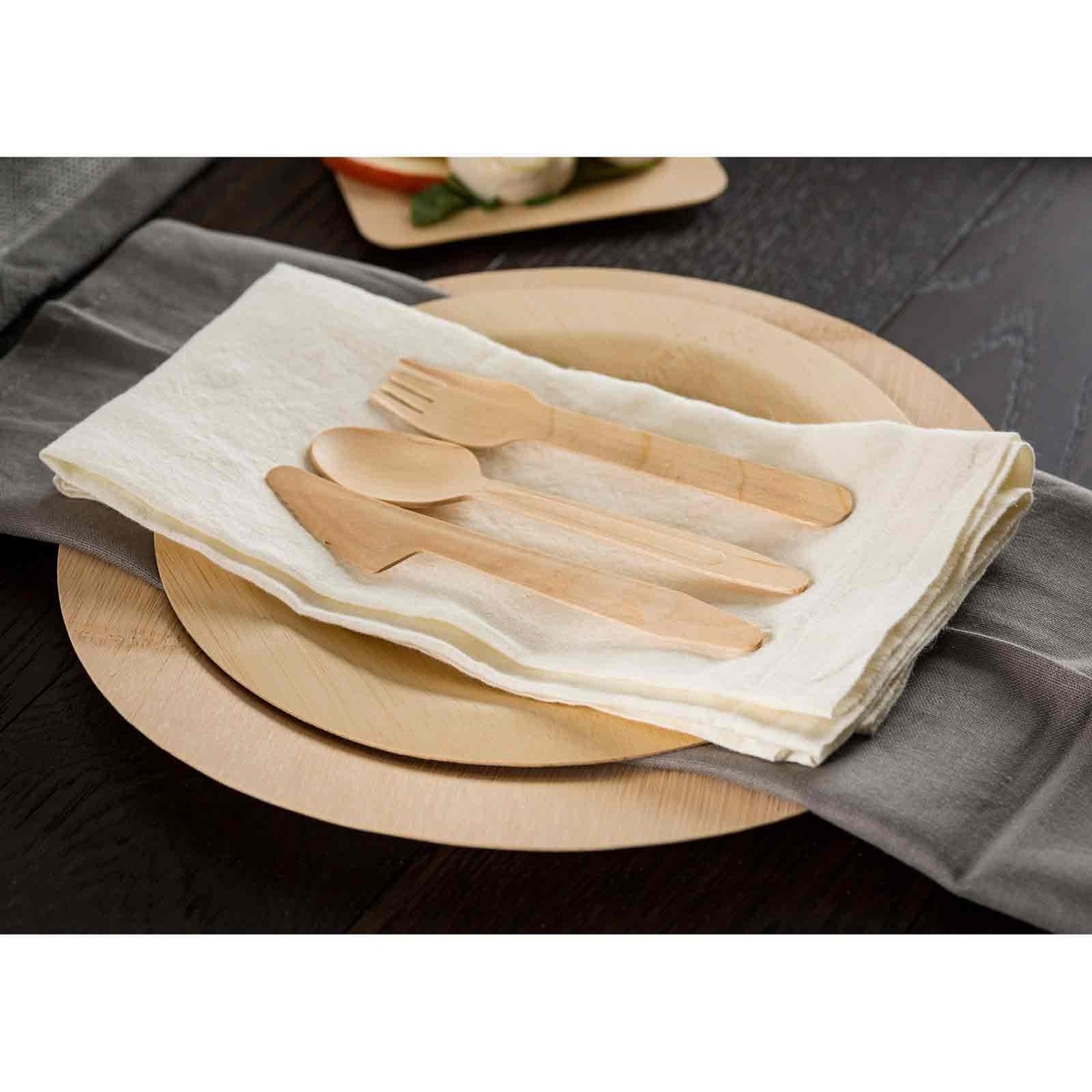 Close up of a bamboo plate with a napkin and wooden utensils