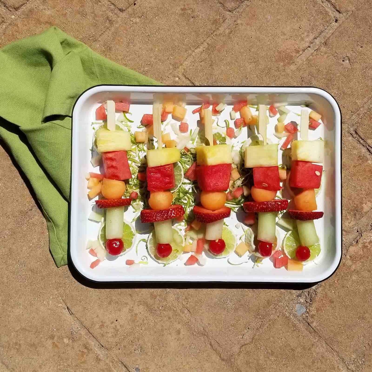 Fruit skewers made with bamboo paddle picks on a white tray