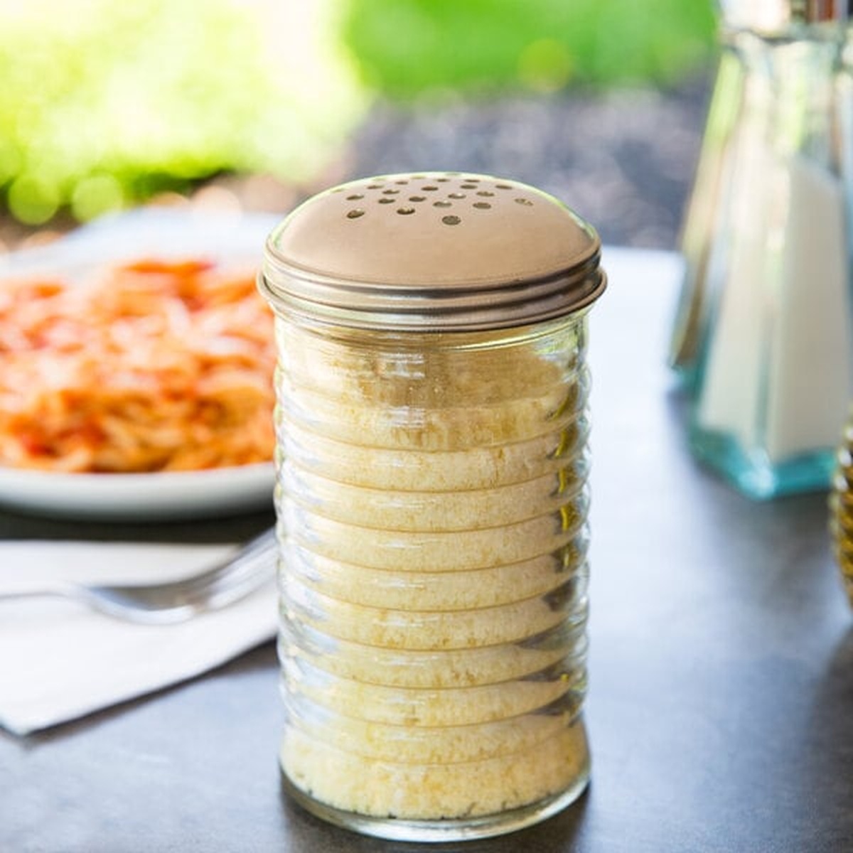 TableCraft BH8800 Beehive glass cheese shaker filled with parmesan, featuring ridged body and perforated stainless steel dome top
